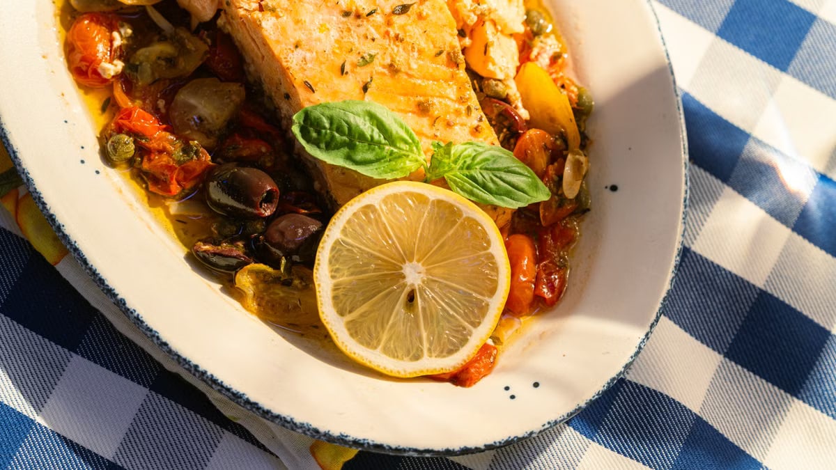 Delicious grilled salmon topped with lemon and basil on a sunlit table.
